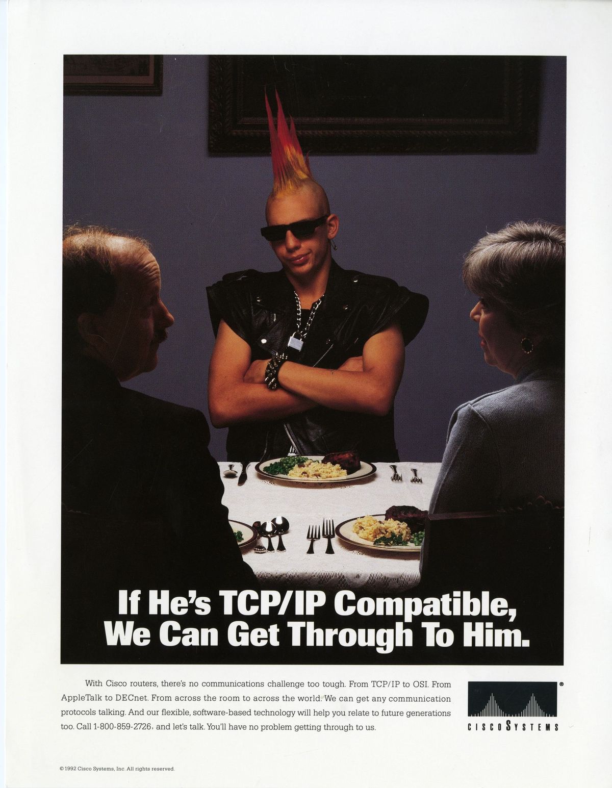A young punk with a pink mohawk sits at a dinner table with his arms crossed and frowning, the shadow of a woman and father implied to be his parents face him, with their back to the camera but their faces tilted in a questioning way. The text "If He's TCP/IP Compatible, We Can Get Through To Him"