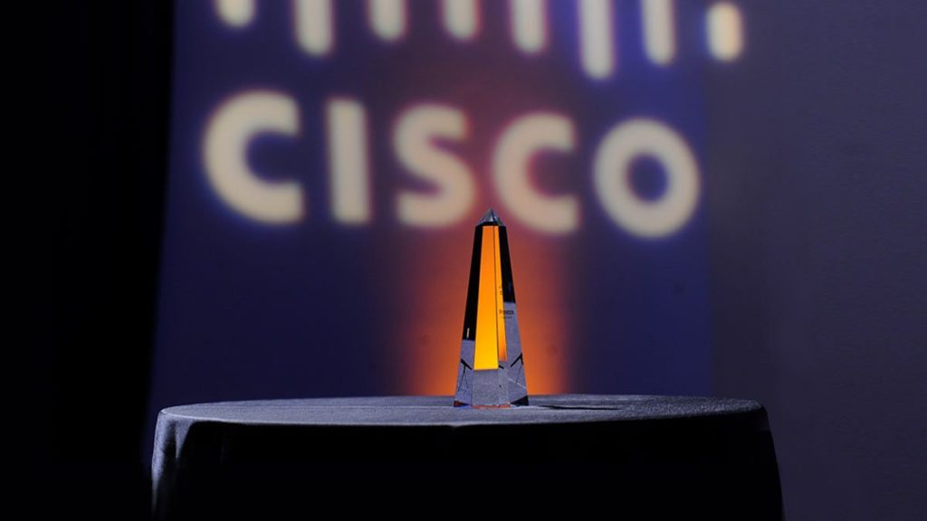 The Cisco Pioneer Award, a glass commemorative in the shape of a pillar, stands on the podium with the words 
