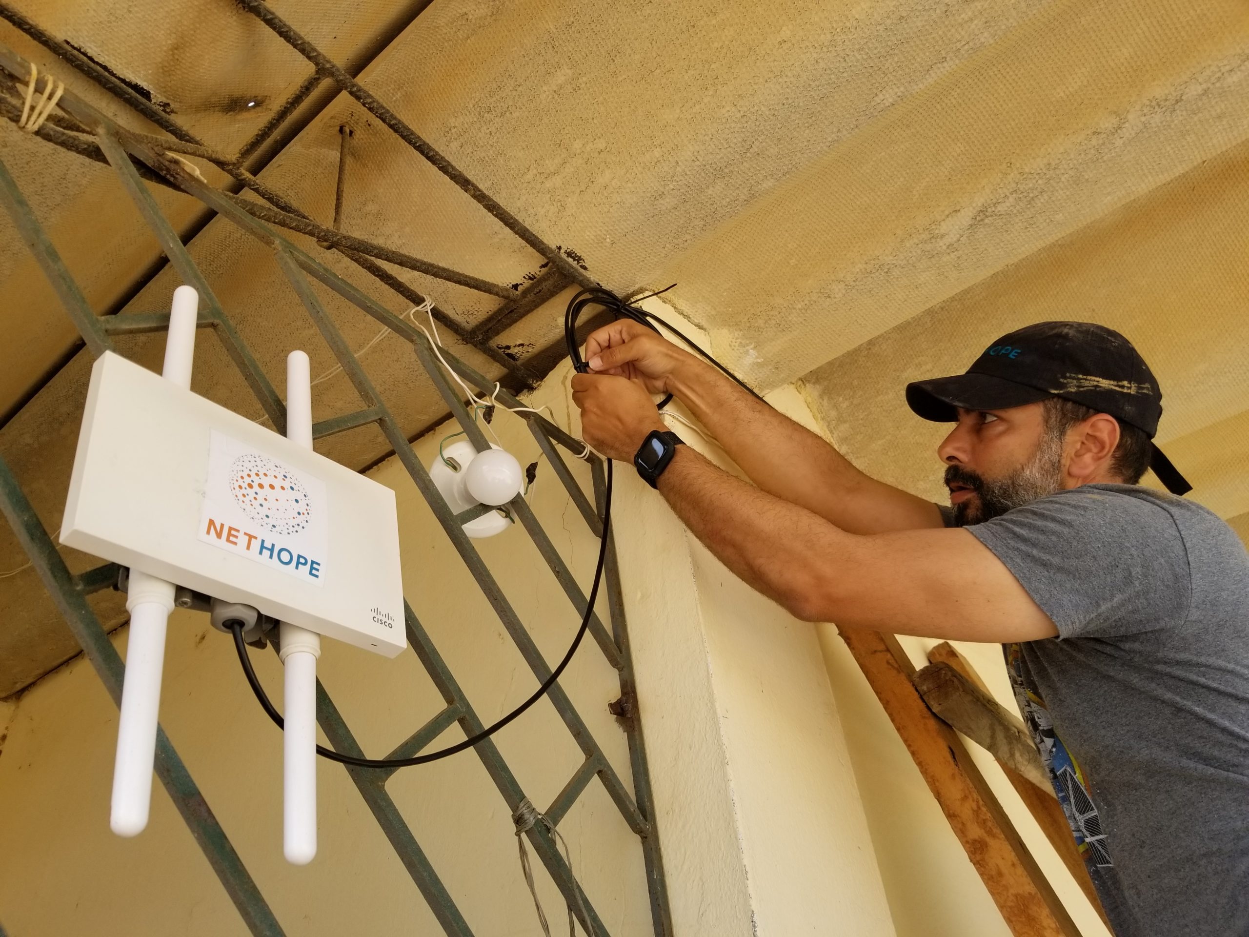 Man installing wireless connection hardware on the outside of a building.