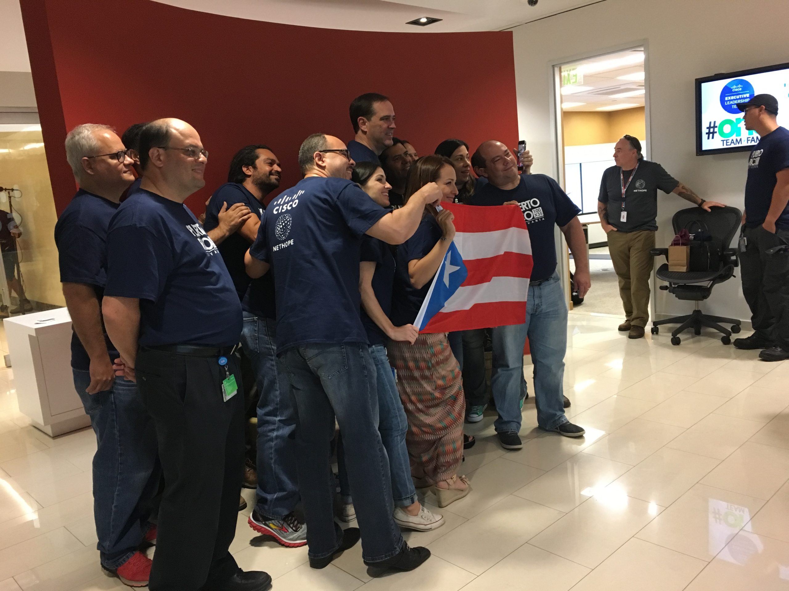 Cisco employees in Cisco office, San Juan, Puerto Rico, holding Puerto Rican flag.